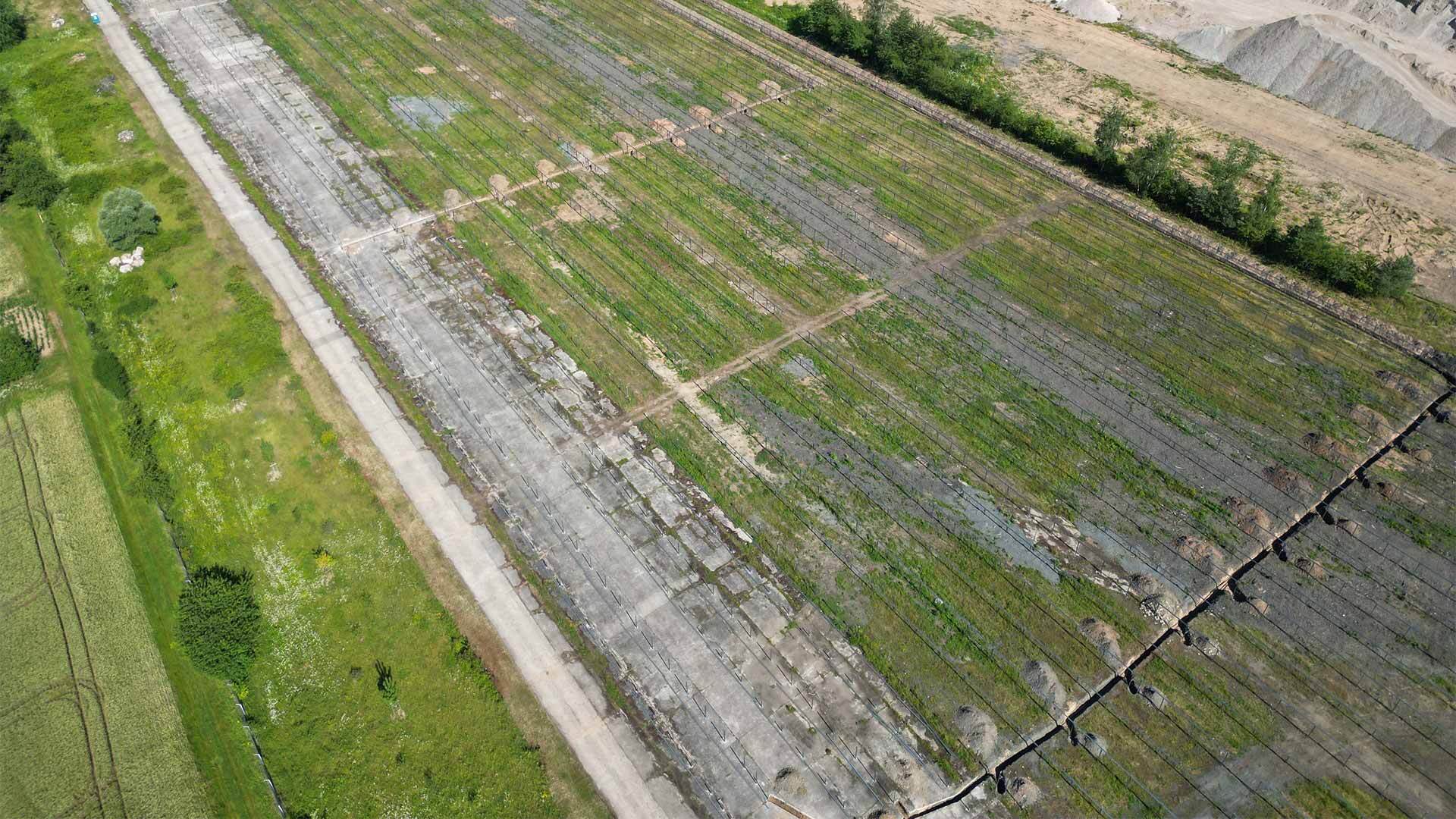 Luftaufnahme einer vorbereiteten Fläche mit Erdarbeiten und begrünten Bereichen für den Bau einer Solaranlage.