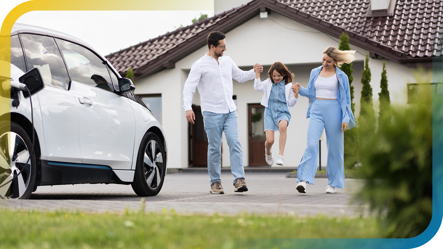 Familie geht fröhlich vor einem Haus, während ein Elektroauto daneben lädt.